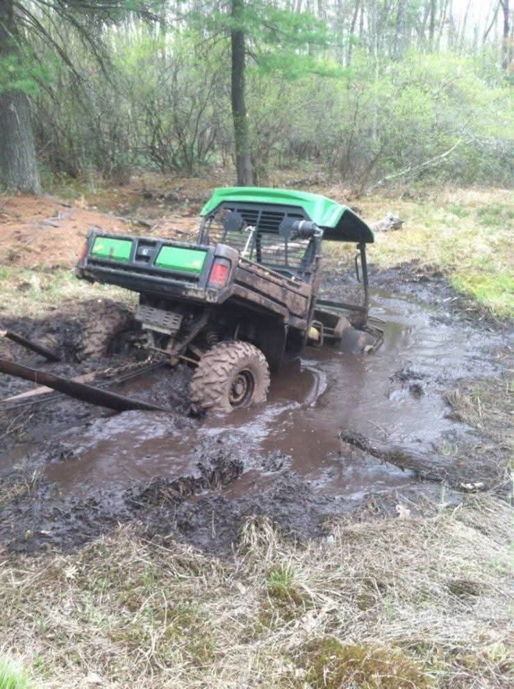 Štvorkolka uviaznutá v bahnitom teréne v lese počas off-road jazdy.