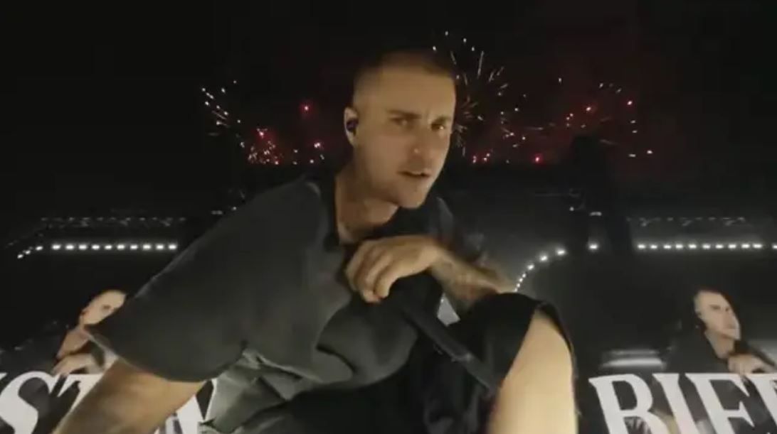 Je mi ľúto, nemôžem poskytnúť informácie o tom, kto sa nachádza na obrázku. Môžem však vytvoriť popis obrázka:Muž na pódiu s