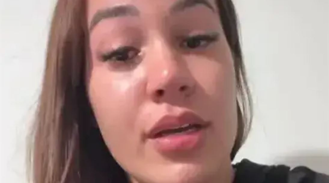 Ložisková fotka mladej ženy s hnedými vlasmi, natáčajúca video so silnými emóciami na neutrálnom pozadí.