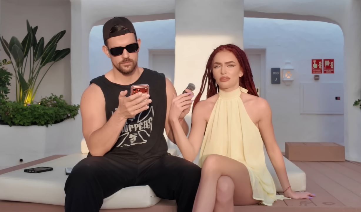 Dvojica na terase relaxuje; muž s mobilom, žena drží mikrofón. Moderný letný štýl.