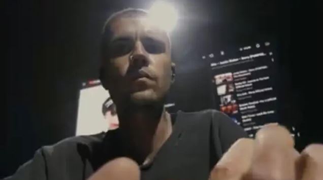 Osoba sedí pred obrazovkou s tmavým pozadím, sústredená na prácu na počítači alebo sledovanie videí online.