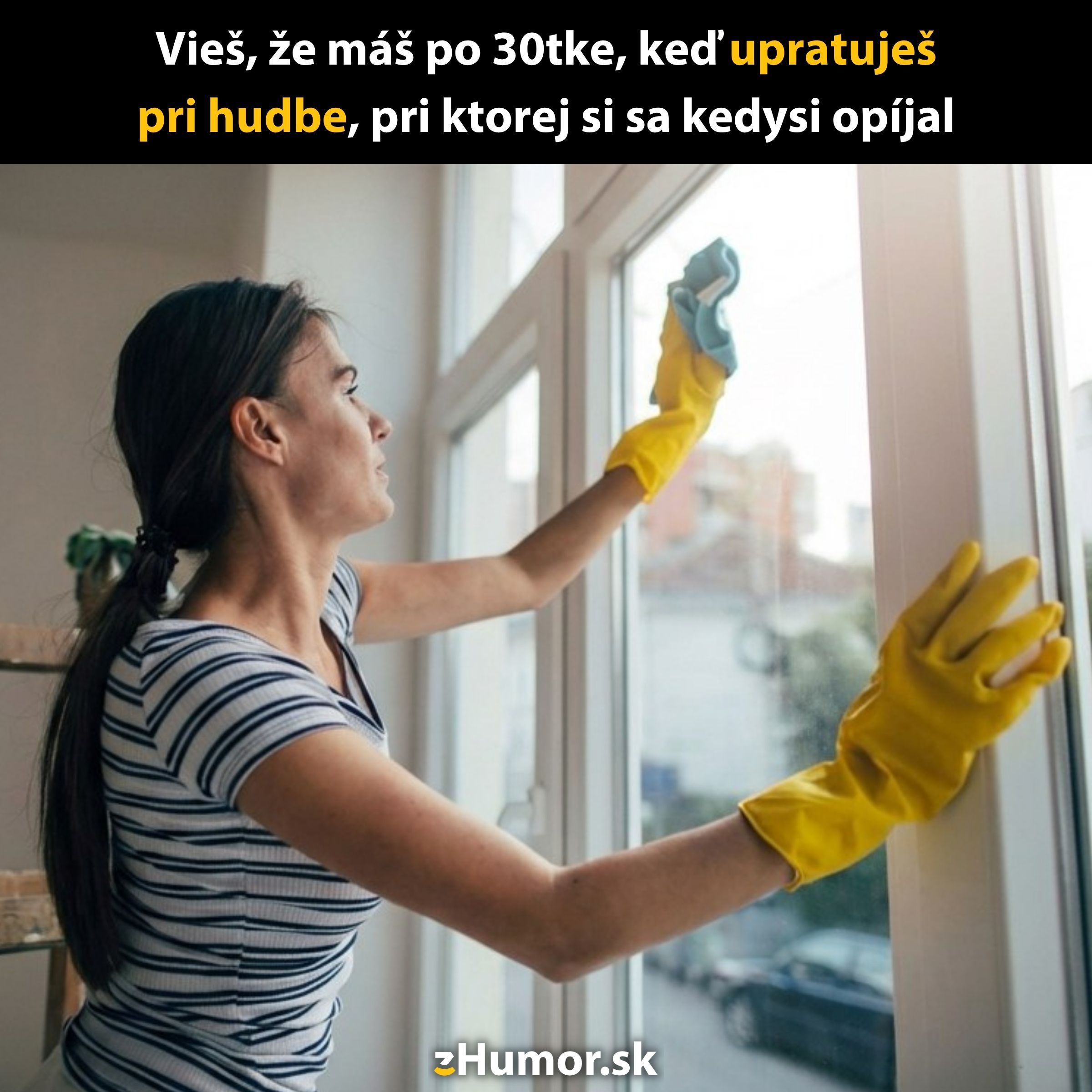 Žena s gumovými rukavicami čistí okno, zatiaľ čo počúva hudbu.