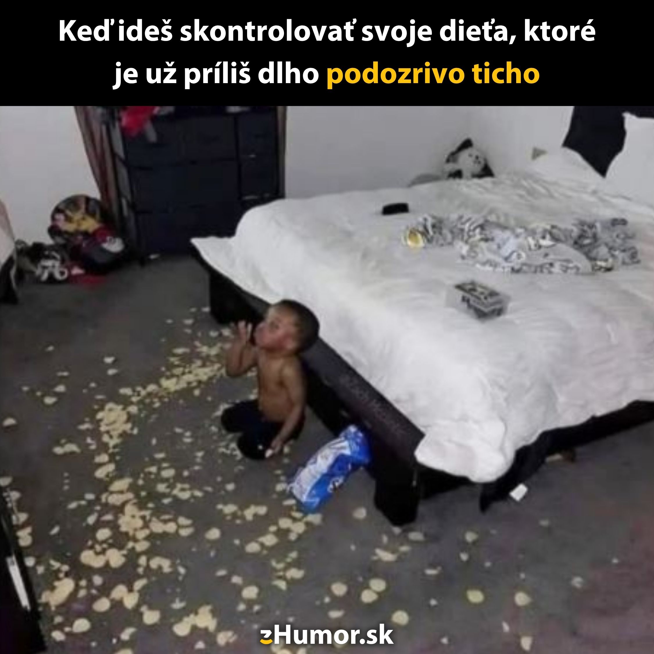 Dieťa sedí na zemi pri posteli, obklopené rozsypanými čipsami, s výrazom nevinnosti.