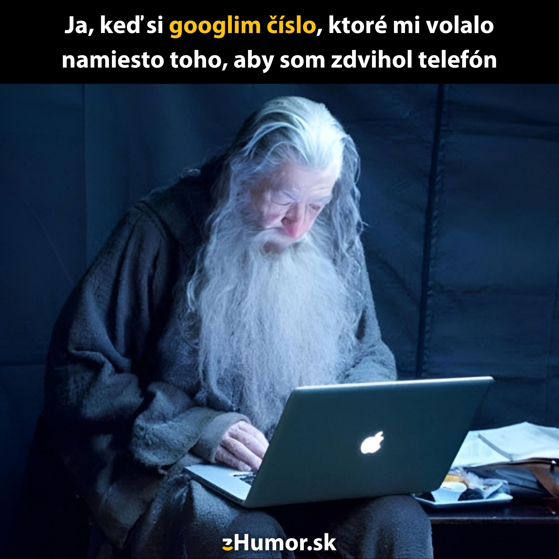 Čarodejník s dlhou bradou sa sústredene pozerá na notebook.