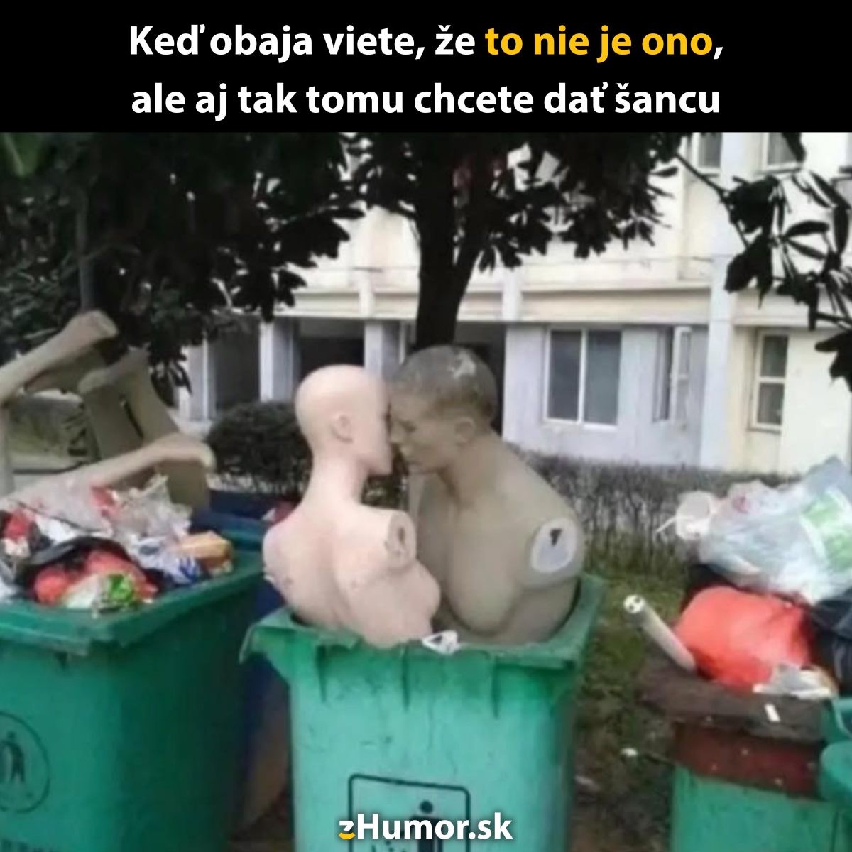 Dve figuríny v kontajneri, ktoré sa dotýkajú nosmi, symbolizujú zvláštny druh romantiky medzi odpadkami.