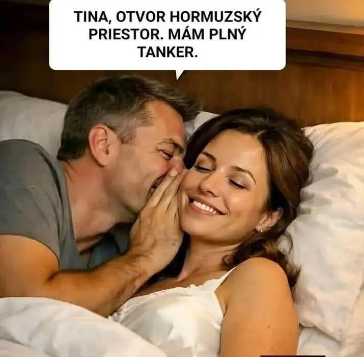 Pár v posteli sa zdieľa úsmevný moment, muž niečo šeptá žene do ucha.