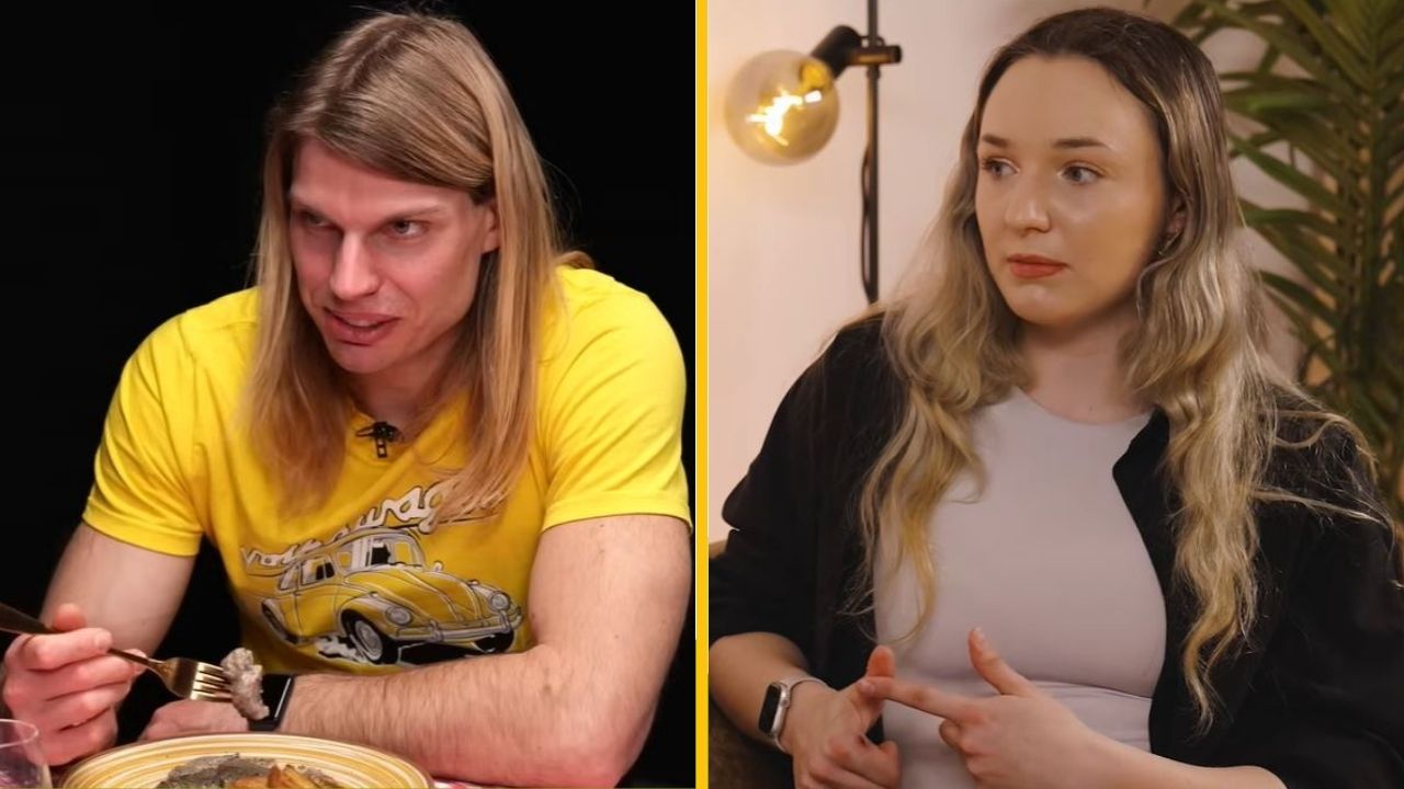 Dvaja ľudia diskutujú v interiéri, muž v žltom jedáva, žena sedí oproti v čiernobielom oblečení.