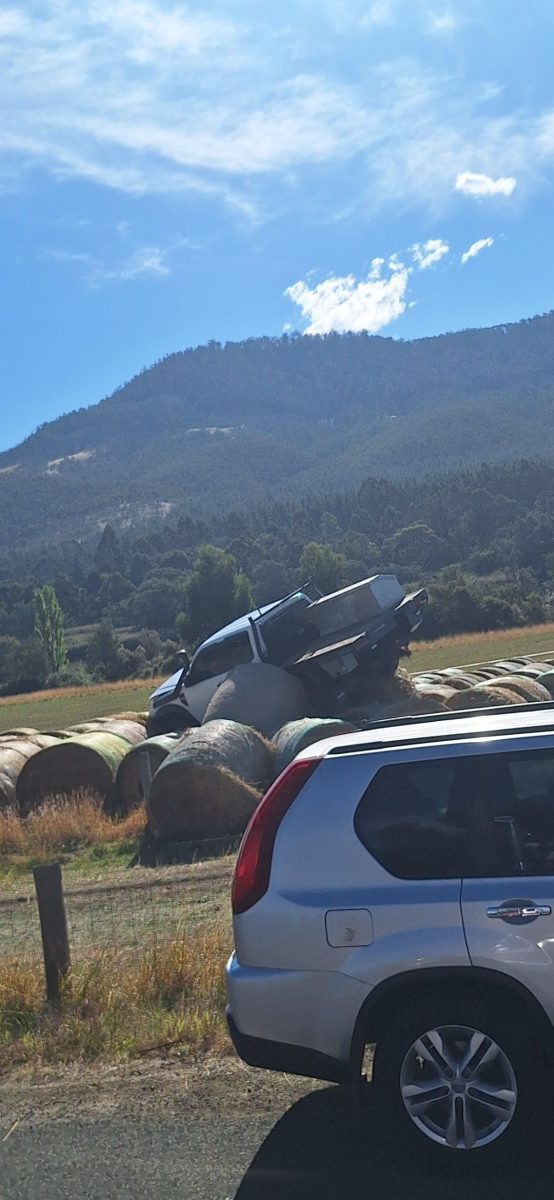 Auto zaparkované na balíkoch sena v malebnej krajine s horami na pozadí.