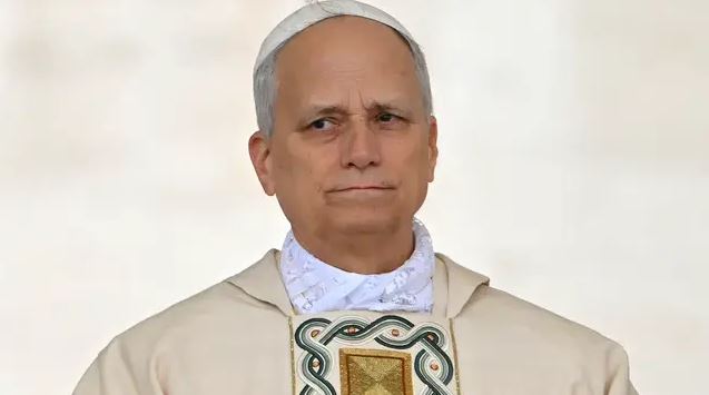 Obrázok muža v liturgickom odeve so symbolickým vzorom. Má vážny výraz tváre a pozerá sa do diaľky.