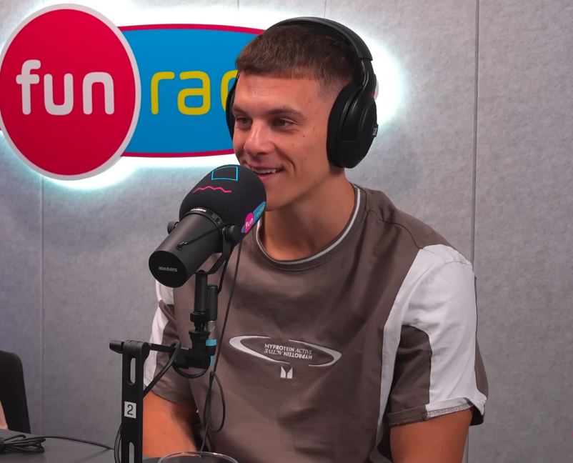 Osoba s mikrofónom v štúdiu rádia Fun držiaca slúchadlá, usmieva sa počas rozhovoru.