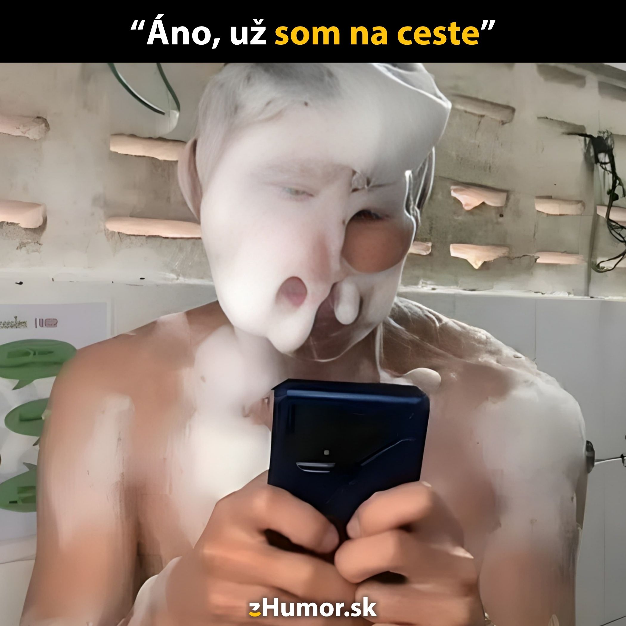 Muž s penou na tvári píše na mobile v kúpeľni, humorný moment multitaskingu.
