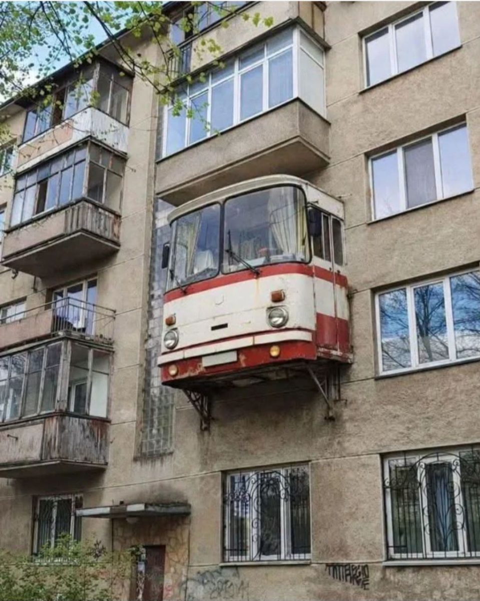 Prestavba starého autobusu ako balkón na paneláku, kreatívna architektúra v mestskej časti.