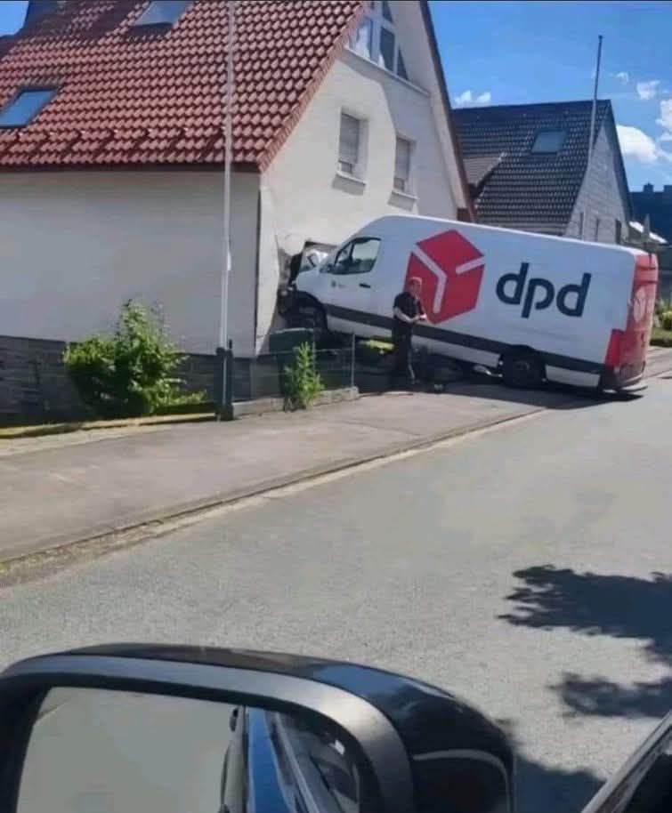Dodávka DPD havarovaná do domu na pokojnej ulici za slnečného dňa.