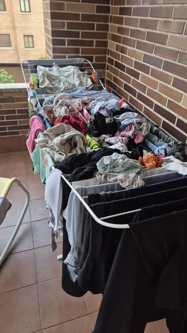 Bielizeň sušiaca sa na sušiaku na balkóne vedľa tehlovej steny.