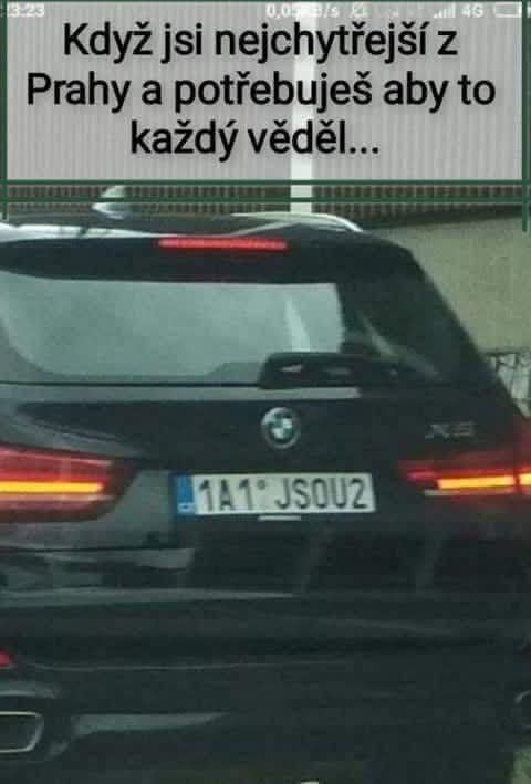 Auto BMW s poznávacou značkou 1A1 JSOU2 a vtipným textom o Prahe na zadnom okne.