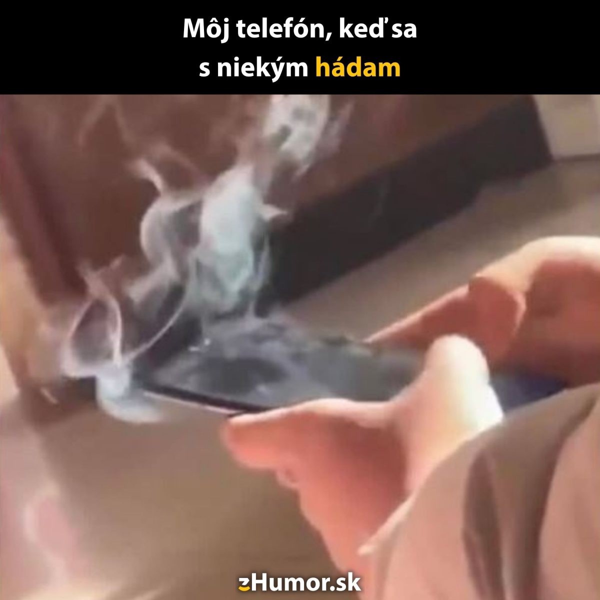 Mobil v rukách, z ktorého stúpa dym, s humorom o intenzívnom hádaní sa cez telefón.