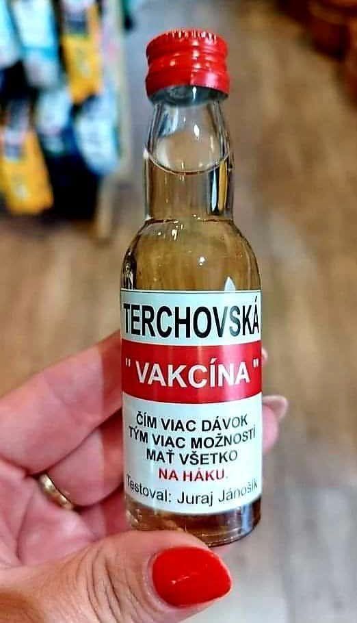 Fľaštička s nápisom Terchovská vakcína ako vtipný suvenír, držiaca v ruke so žiarivým červeným lakom.