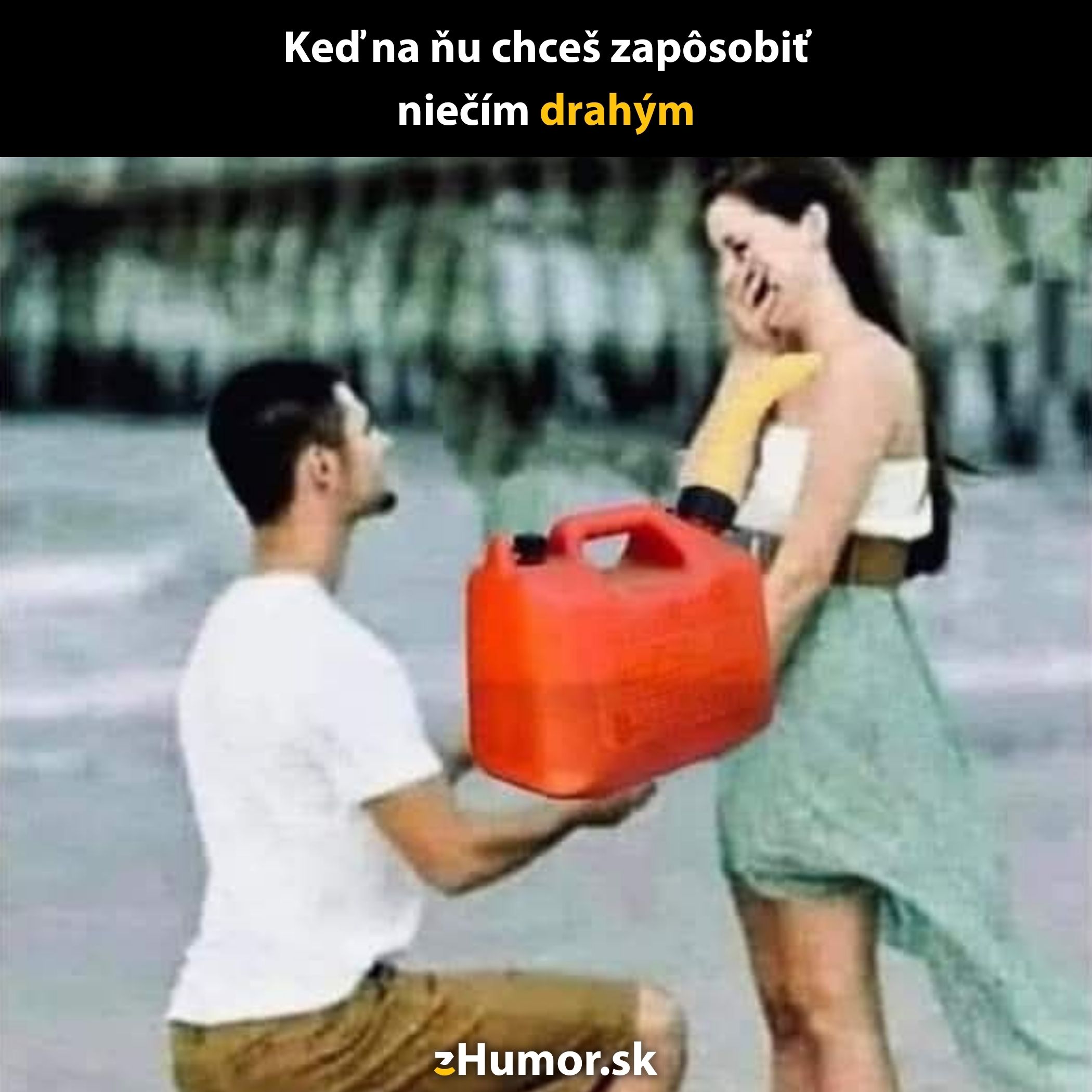 Muž kľačiaci na pláži drží kanistru benzínu, žena sa usmieva a zakrýva si ústa rukou.