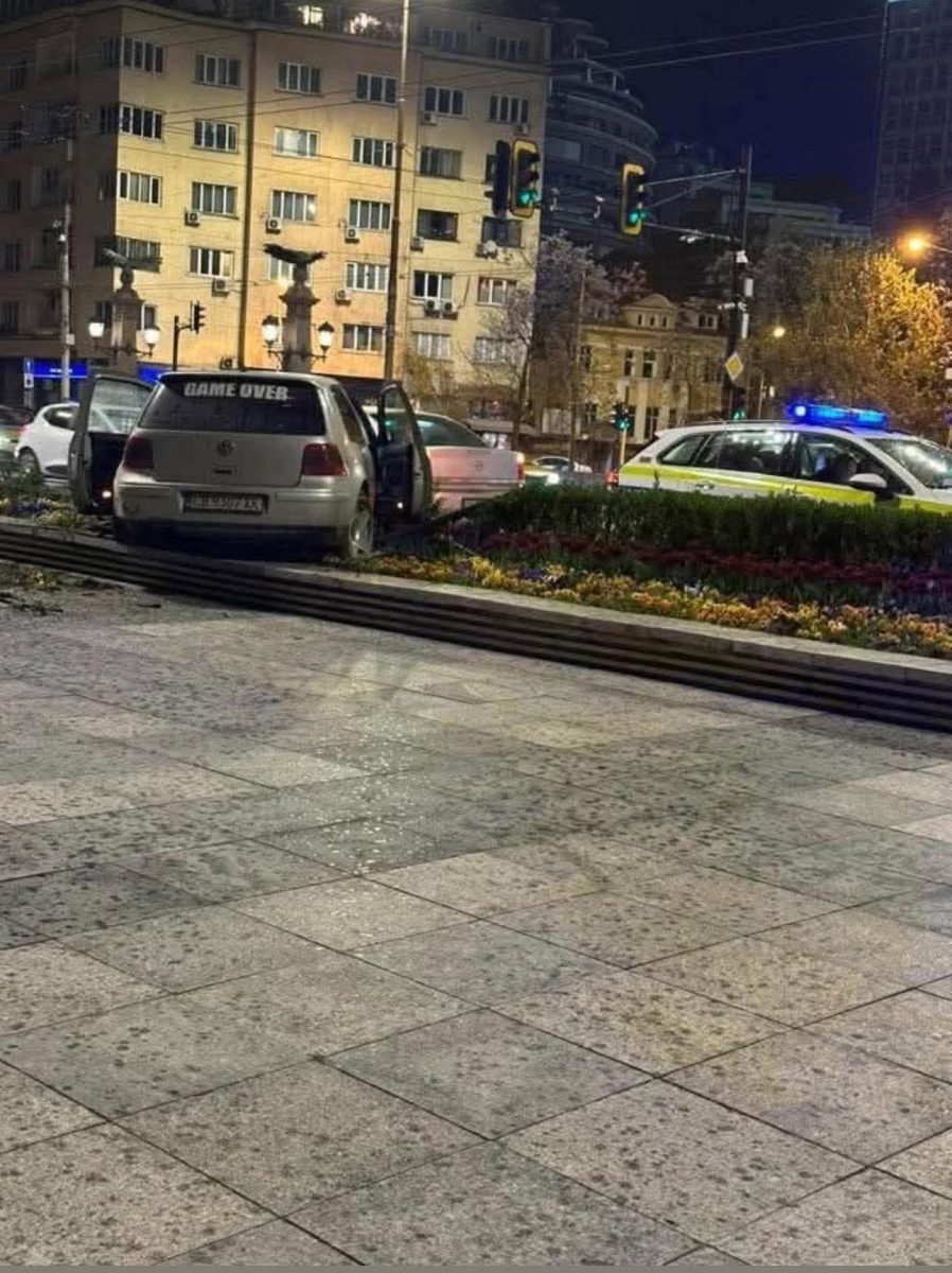Auto na obrubníku s otvorenými dverami a políciou v pozadí, večerná scéna v meste.