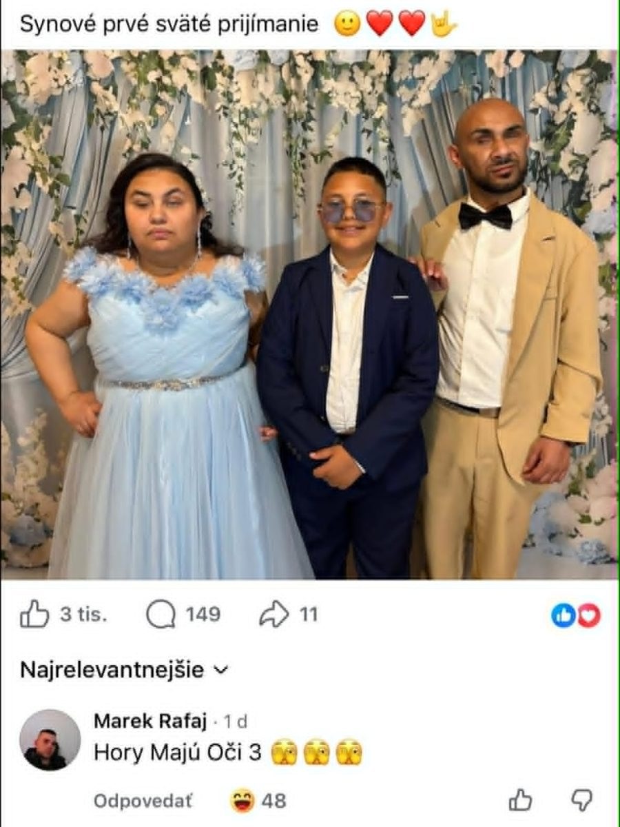 Rodinná fotka z prvého svätého prijímania, modré šaty, oblek, kvetinová dekorácia na pozadí.