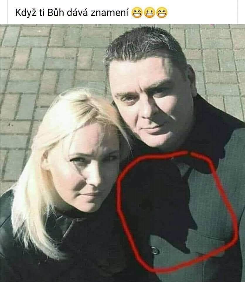Dvaja ľudia s tieňom pripomínajúcim kríž na zemi, zachytení počas dňa na dlažbe.