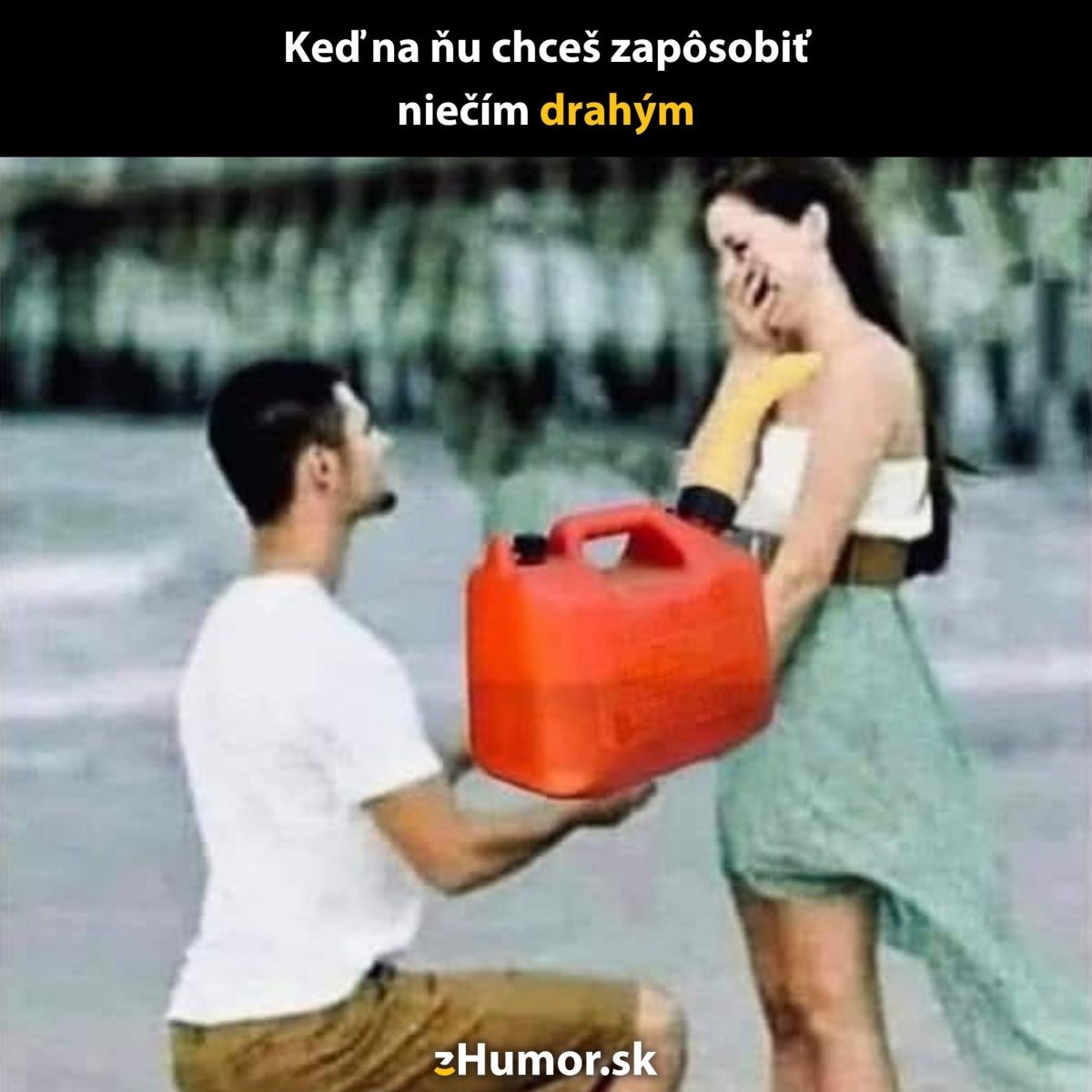 Muž ponúka žene kanister s benzínom ako prekvapivý darček na pláži, snaha o humor.