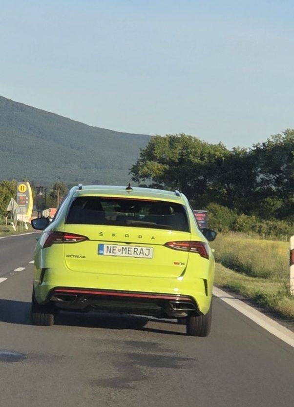 Jasne žltá Škoda Octavia s poznávacou značkou NE-MERAJ na ceste, okolitá príroda s horami v pozadí.
