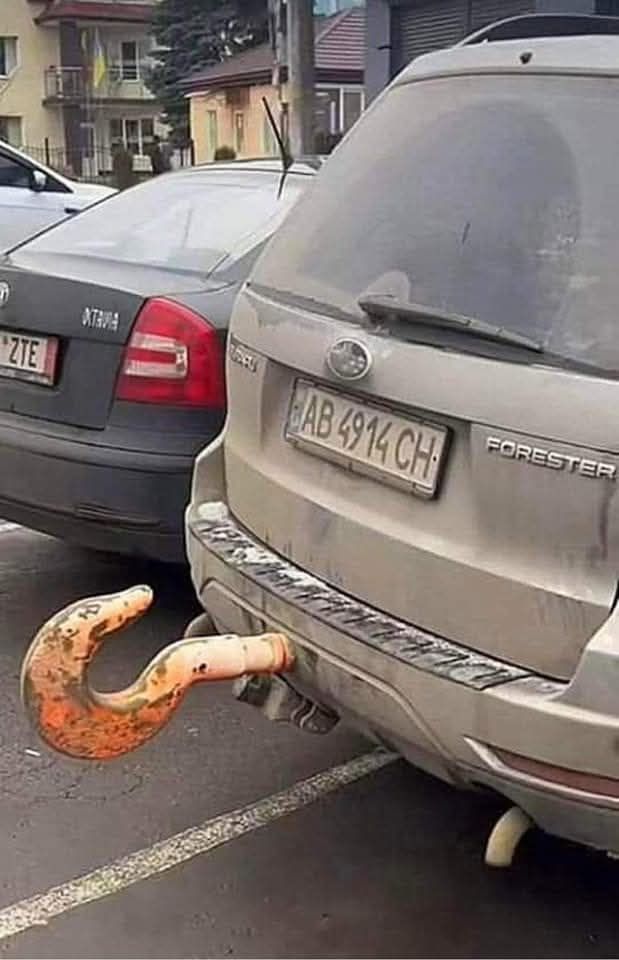Auto s neobvyklým veľkým hákom namiesto ťažného zariadenia zaparkované na parkovisku.