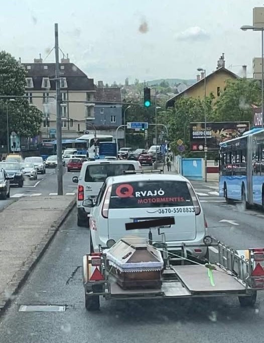 Auto vezúce rakvu na diaľnici, netradičná scéna v mestskom prostredí.