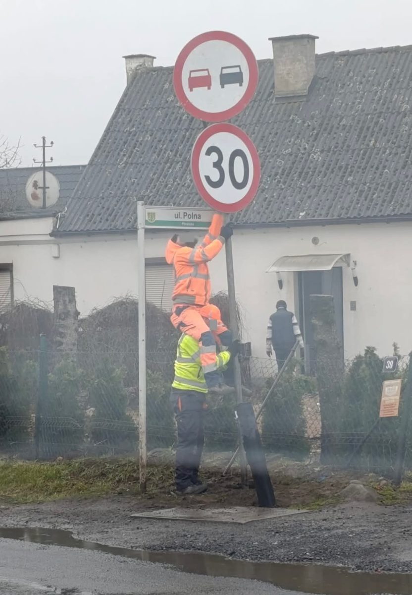 Pracovníci v reflexných vestách inštalujú dopravné značky na ulici Polna, rýchlosť obmedzená na 30 km/h.