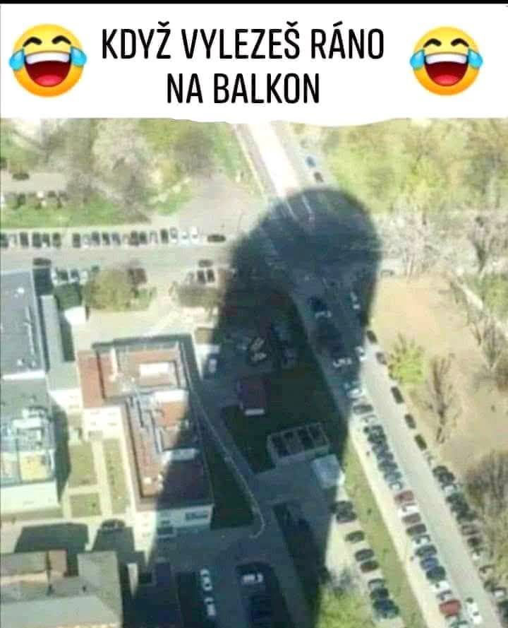 Ranný pohľad z balkóna: obrovský tieň na parkovisku vyzerá ako postava s úsmevom.