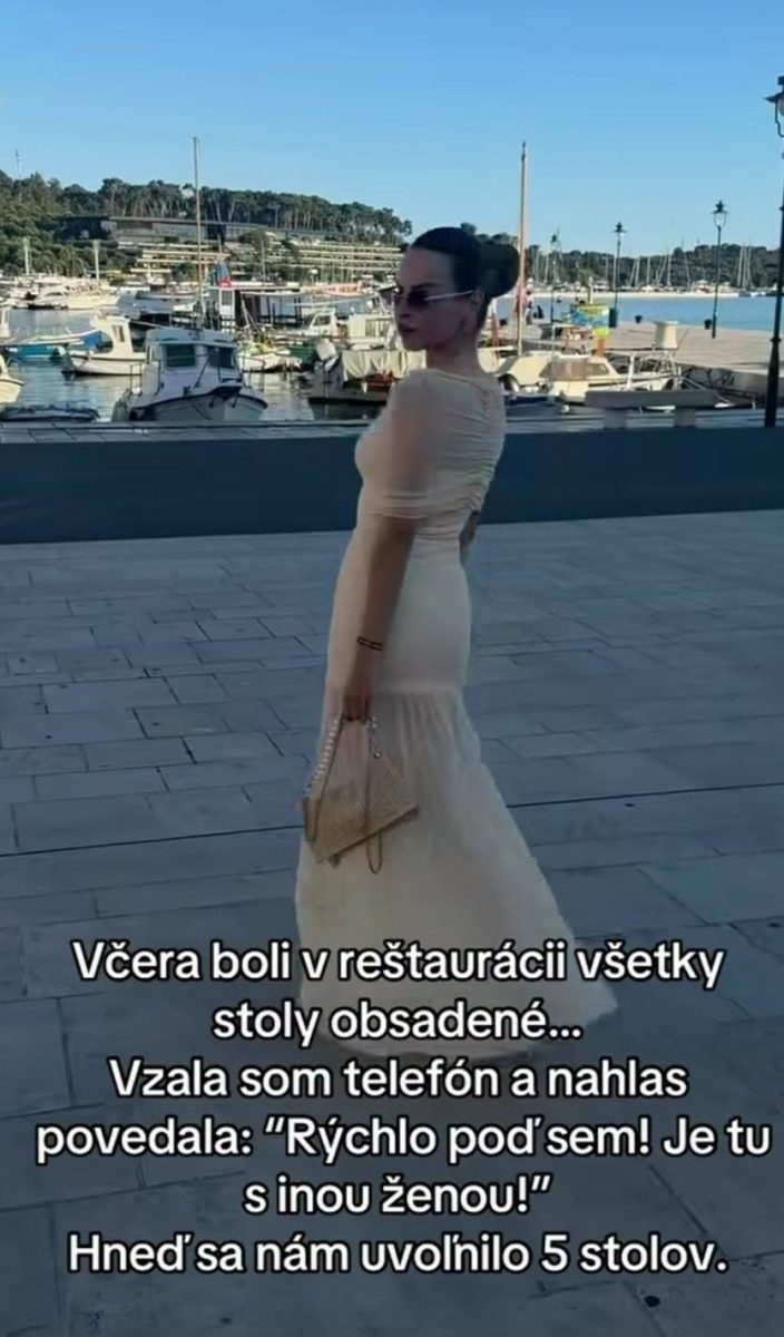 Žena v bielej šaty pri prístave so správou o obsadených stoloch v reštaurácii.