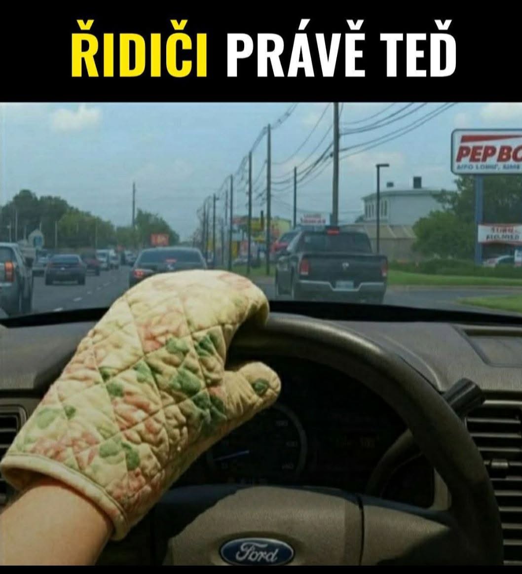 Vodič s chňapkou na volant v aute značky Ford, nápis ŘIDIČI PRÁVĚ TEĎ, zobrazuje letnú paródiu na horúce riadenie.