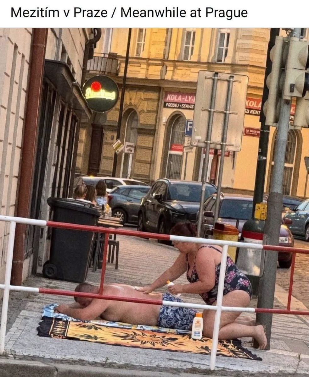 Osoba relaxuje na chodníku v Prahe, zatiaľ čo iná aplikuje opaľovací krém. Urbanistická improvizácia.