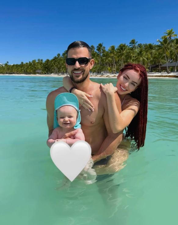 Šťastná rodina vo vode na tropickej pláži pod modrou oblohou.