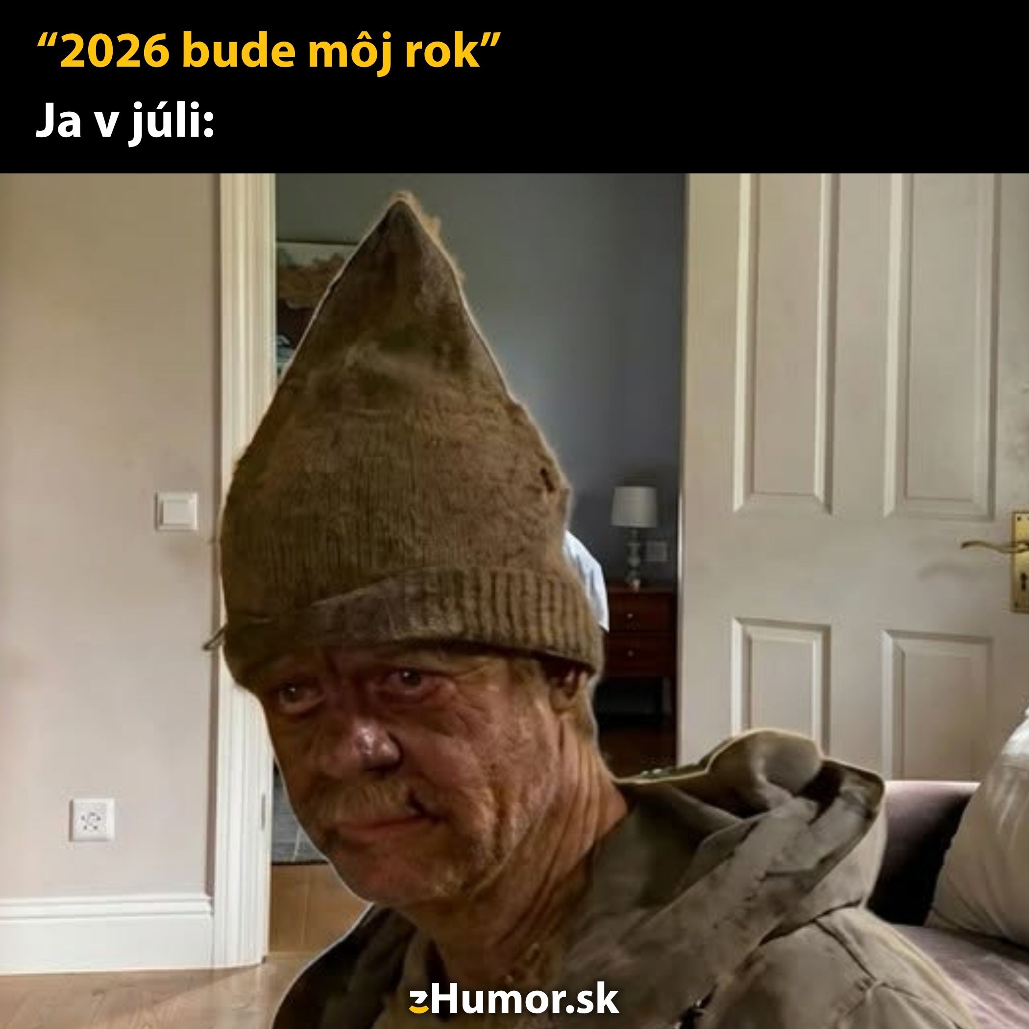 Muž v starom oblečení a čiapke doma s vtipným textom: 2026 bude môj rok a Ja v júli.