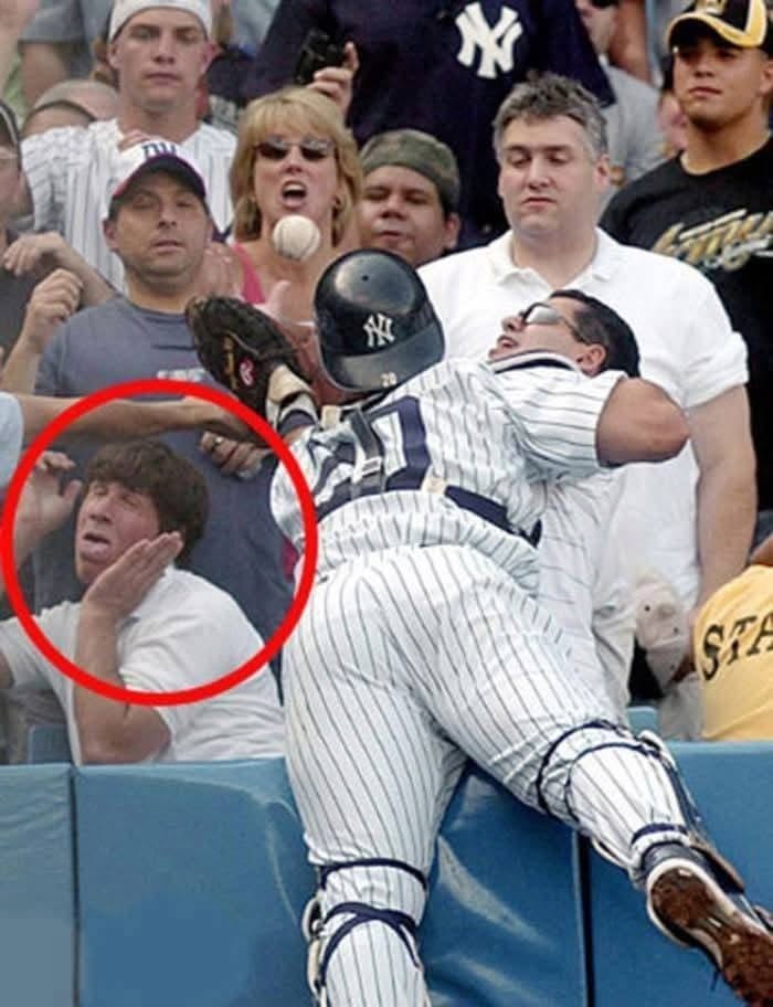 Baseballový hráč sa snaží chytiť loptu, zatiaľ čo fanúšikovia sledujú s prekvapením a strachom na tvárach.