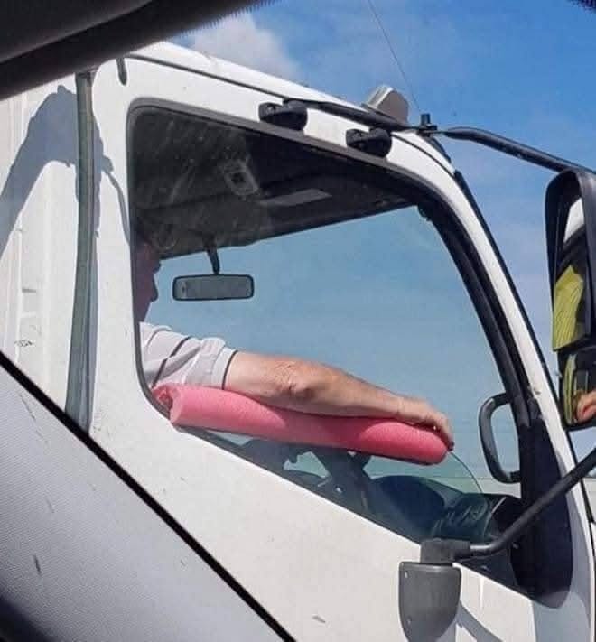 Vodič kamiónu si opiera ruku o ružový plavák na ramene, relaxuje počas jazdy.