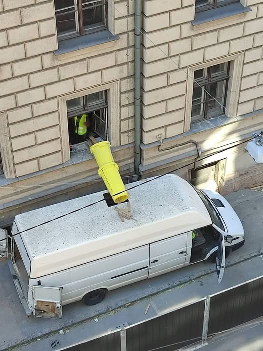 Stavebný odpad sa sype z okna do bielej dodávky pomocou žltého žľabu.