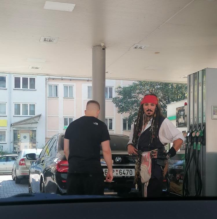 Muž pri tankovaní auta s kostýmo Pirátov z Karibiku na čerpacej stanici.