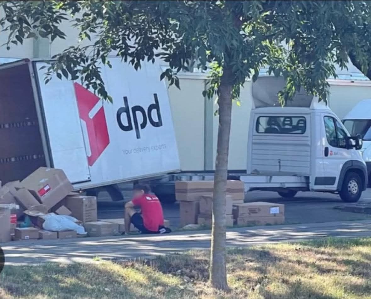 Dodávka DPD vykladá balíky na chodníku; strom poskytuje tieň.