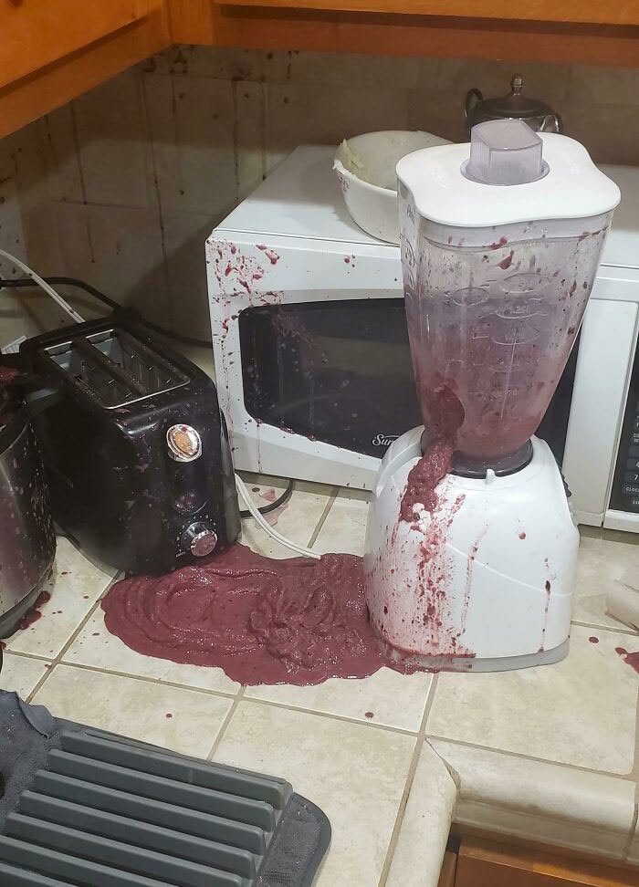 Rozliaty smoothie z mixéra na kuchynskej linke vedľa mikrovlnky a hriankovača.