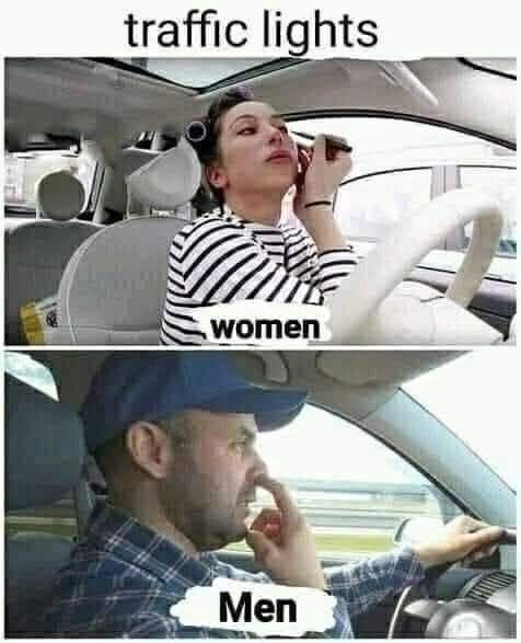 Žena sa líči za volantom, muž si čistí nos. Humorná chvíľa na semaforoch počas šoférovania.