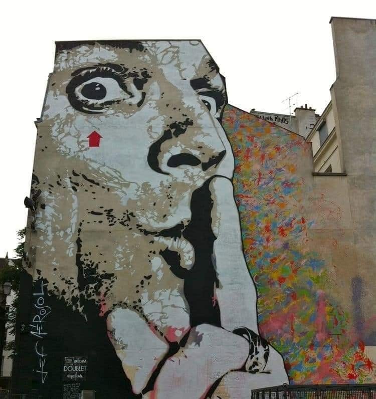 Grafitový portrét na stene, osoba so symbolom mlčania, farebné abstraktné pozadie.