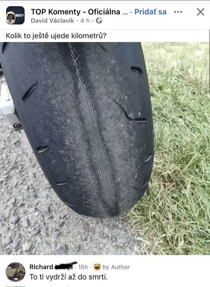 Opotrebovaná motocyklová pneumatika na vidieckej ceste, záber na stred s minimálnym dezénom.
