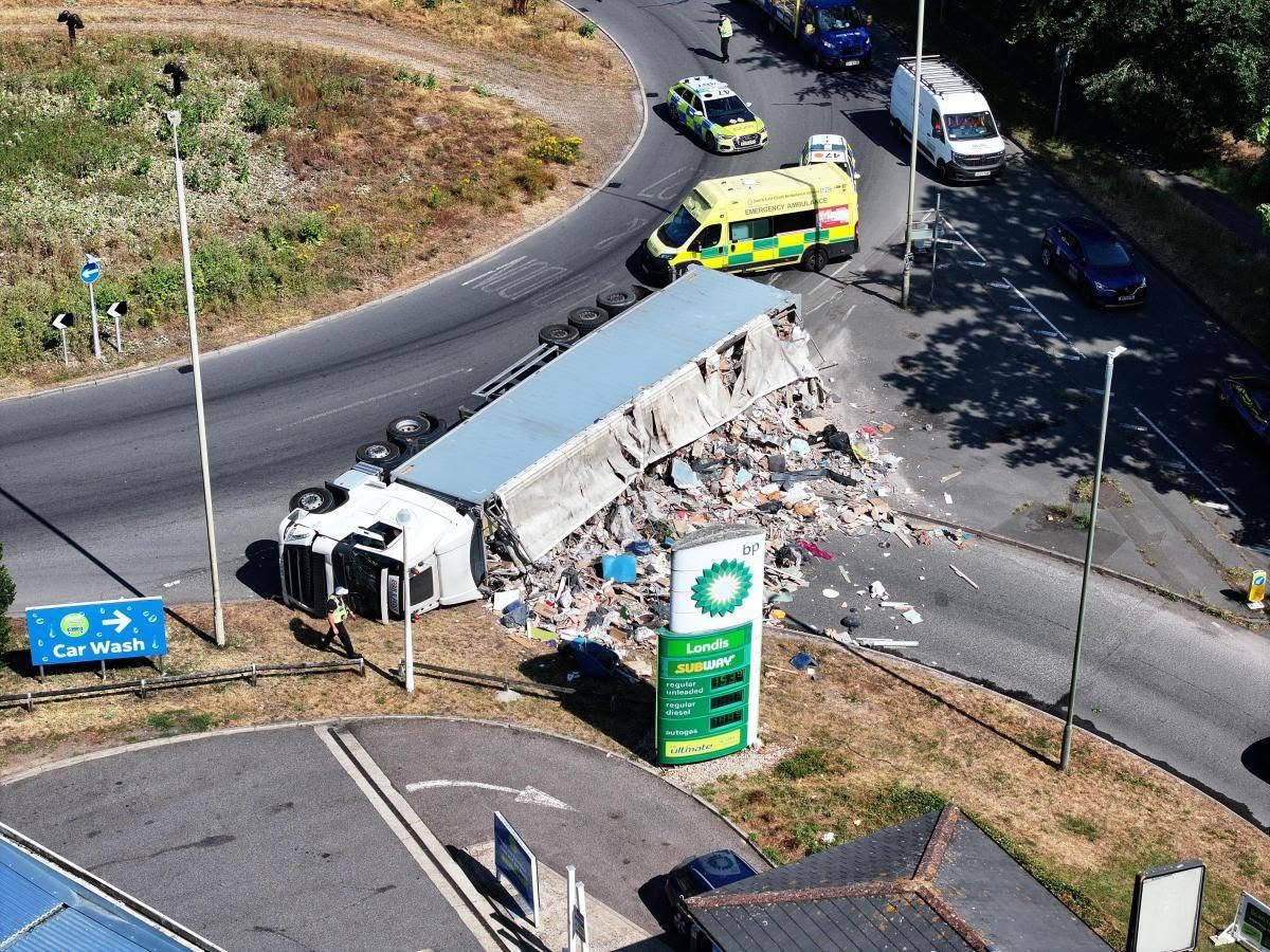 Prevrátený kamión na kruhovom objazde, policajné a záchranné vozidlá na mieste nehody.