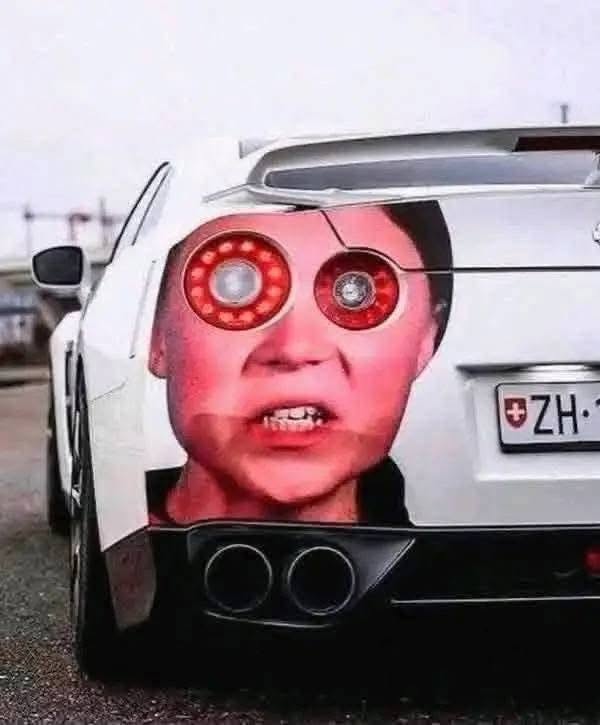 Auto so zadnými svetlami a vtipným polepom tváre, ktorá pripomína oči a ústa.