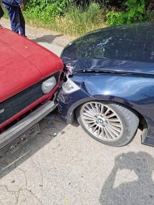 Dopravná nehoda medzi červeným a modrým vozidlom na ceste, poškodenie predných častí áut.