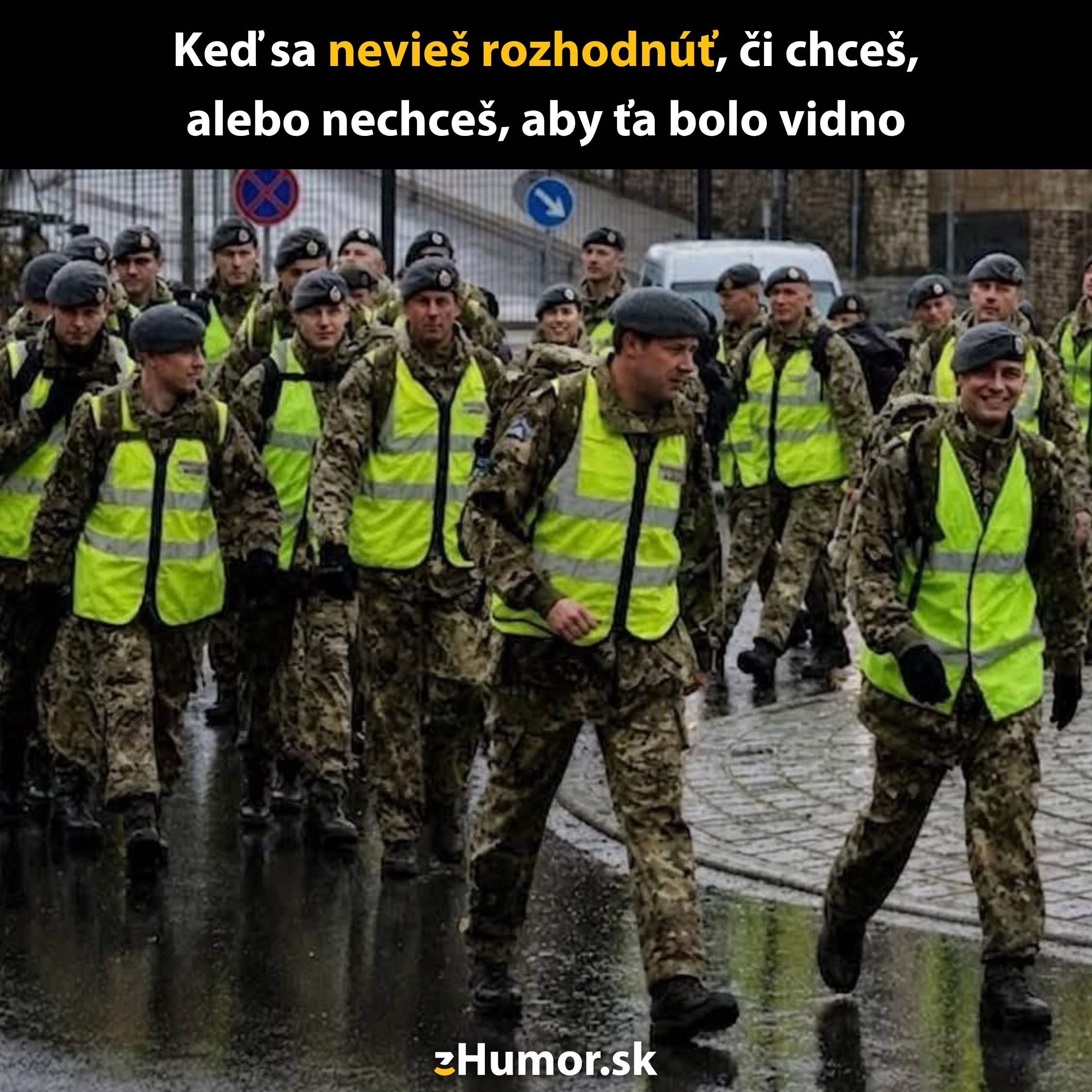 Skupina vojakov v maskovacích uniformách a reflexných vestách kráča po daždivých uliciach mesta.