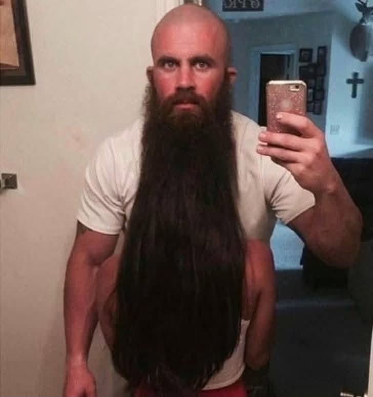 Muž s dlhými vlasmi si robí selfie pred zrkadlom, ilúzia brady.